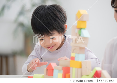 客廳裡,一個蹣跚學步的孩子在玩積木。 客廳裡,一個蹣跚學步的孩子在玩積木。 135849368