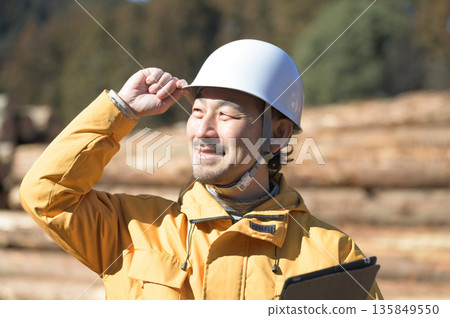 A man in work clothes wearing a helmet and looking up 135849550