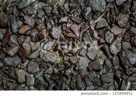Ballast stone gravel soaked with engine oil in the railroad tracks. Ballast stone gravel soaked with engine oil in the railroad tracks. 135849951