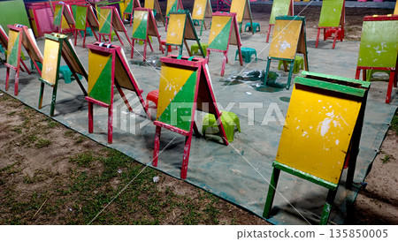 Row of Painted Wooden Easels at Outdoor Children Art Workshop in Night Festival Row of Painted Wooden Easels at Outdoor Children Art Workshop in Night Festival 135850005