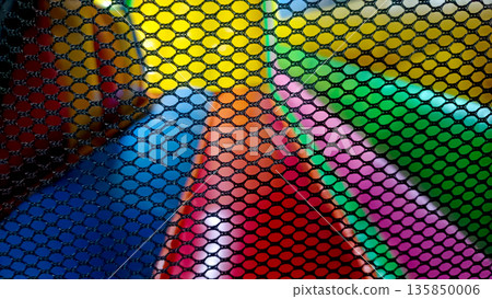 Close Up of Black Safety Net with Blurred Colorful Inflatable Playground Background Close Up of Black Safety Net with Blurred Colorful Inflatable Playground Background 135850006