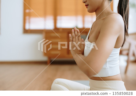 Young Asian woman meditating in lotus position at home 135850028