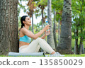 Young Asian woman in activewear sitting under a tree 135850029