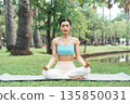 Asian woman meditating in a peaceful park setting 135850031