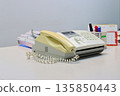 A fax machine on a desk with paper loaded, ready to send documents in an office setting 135850443