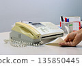 Man hands using a fax machine, putting paper in and sending fax in office 135850445
