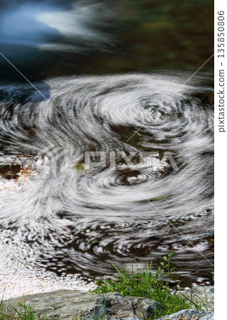 A fantastic water surface with swirling cherry blossom petals_Vertical A fantastic water surface with swirling cherry blossom petals_Vertical 135850806