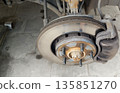 Wheel-off view of a used disc brake assembly showing surface rust on the hub and wear on the rotor, indicating a need for inspection or service work 135851270