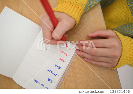 空拍特寫鏡頭，拍攝到一位女士正在記錄日程安排的雙手。 135851406