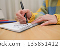 特寫鏡頭：一位女士的手正在筆記本上寫字。 135851412