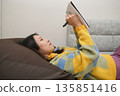 日記圖片：一位女士躺著在筆記本上寫字。 135851416