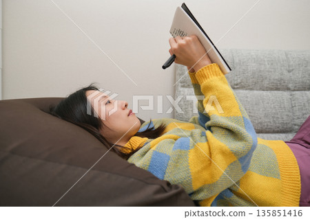 日記圖片：一位女士躺著在筆記本上寫字。 135851416