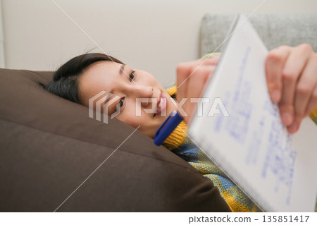 日記圖片：一位女士躺著在筆記本上寫字。 135851417