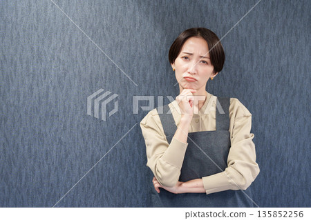 一位穿著圍裙、正在思考的女職員 135852256