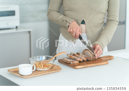 女人的手在廚房切麵包做早餐。 135854359