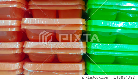 Vibrant Orange and Green Plastic Food Containers in Plastic Wrap 135854388