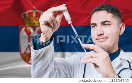 Doctor holding syringe on Serbia flag background. Medical professional holding syringe with Serbian flag in the background 135854705