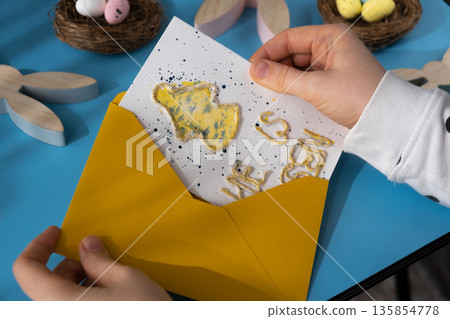 Person holding handmade greeting card with message HE IS RISEN written in beautiful handwriting. Gesture shows excitement and joy for the upcoming event. Springtime holiday gift present zero cost 135854778