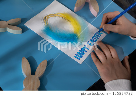 Creating Easter egg with cotton rope and colorful feather Storytelling of creating craft Easter greeting card holiday present. Tactile hand-on activity. Master class progress of creative me-made gifts 135854782