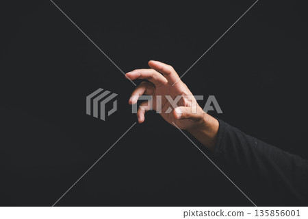 Closeup of a man hand in a dramatic pose, making a gesture or sign to reach for something on a dark background, a symbolic sign showing the concept of wanting something 135856001
