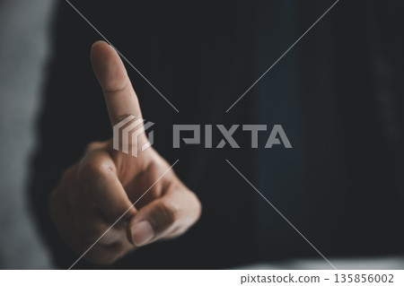 Close-up of a hand with one finger pointing towards the viewer against a dark background. Close-up of a hand with one finger pointing towards the viewer against a dark background. 135856002