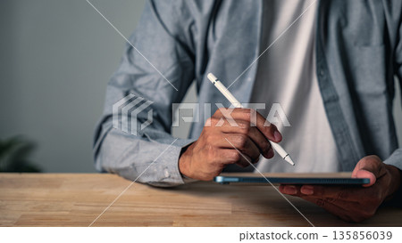 A man using a hand gesture to sign a document holds a professional business pose, a confident modern worker striking a second pose to show digital workflow and technology 135856039