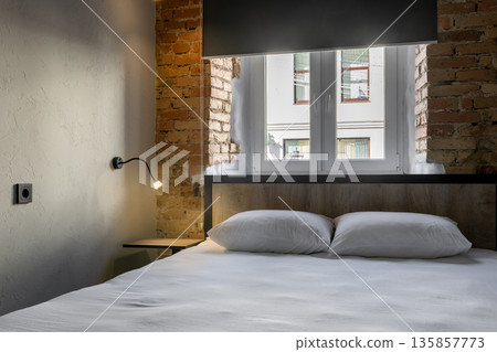 Close-up of a cozy double bed in a loft hostel room with an exposed brick wall 135857773