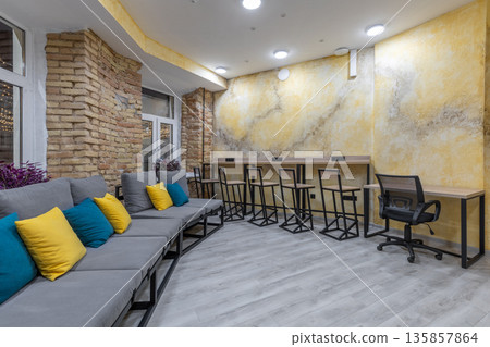 Spacious hostel lounge with long grey sofa and bar counter at night Spacious hostel lounge with long grey sofa and bar counter at night 135857864
