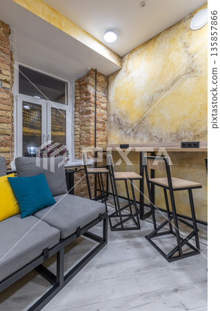 Modern hostel common area with bar seating and cozy sofa at night 135857866