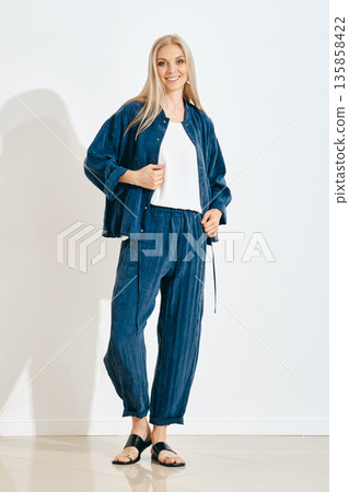 Woman posing in casual outfit with blue fabric in a bright indoor space Woman posing in casual outfit with blue fabric in a bright indoor space 135858422