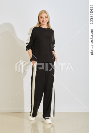 Woman modeling stylish black and white athletic outfit indoors in bright light Woman modeling stylish black and white athletic outfit indoors in bright light 135858435