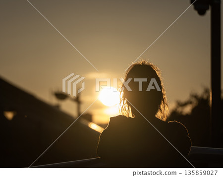 A woman looking at the setting sun A woman looking at the setting sun 135859027