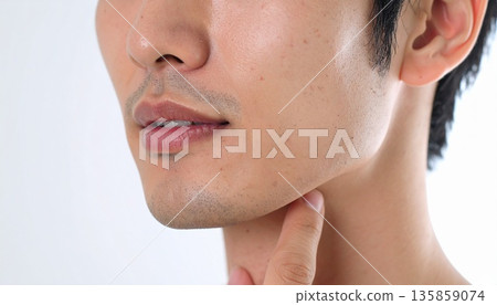 一位年輕男子的臉，留著藍色的鬍鬚，部分區域未刮乾淨。特寫鏡頭聚焦於他的嘴部和下巴。這張圖片與男士護膚、美容和除毛有關。 135859074