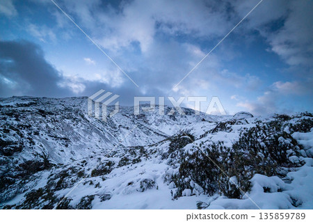 The rugged and majestic mountain scenery of Hokkaido, with snow and clouds spreading across Mount Meakan in winter 135859789