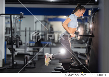 Woman exercising on fitness machine for strength training Woman exercising on fitness machine for strength training 135860091