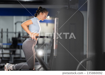 Woman exercising on assisted dip machine training arms Woman exercising on assisted dip machine training arms 135860092