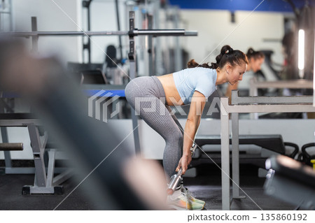 Woman exercising deadlift with barbell in modern gym Woman exercising deadlift with barbell in modern gym 135860192