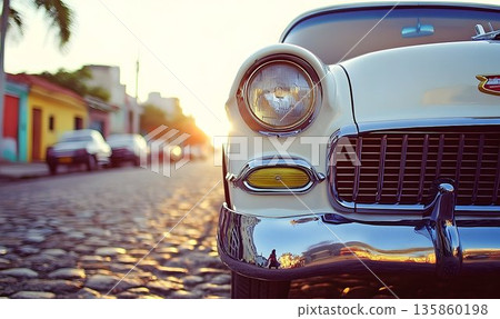 Classic Car's Headlight and Chrome Reflecting Sunset on Cobblest 135860198