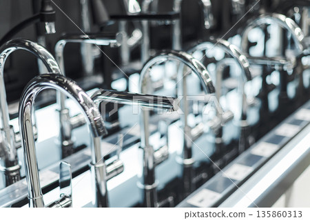 Rows of sleek chrome faucets displayed in a showroom, representing modern bathroom and kitchen design 135860313