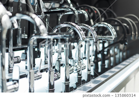 Rows of sleek chrome faucets displayed in a showroom, representing modern bathroom and kitchen design 135860314