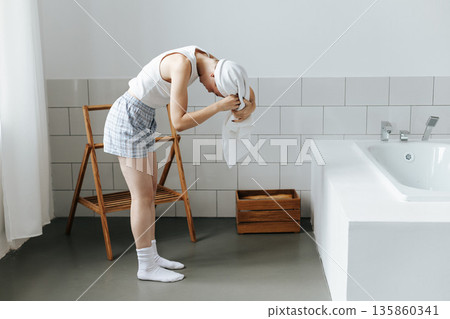Young woman wrap white towel over head in bathroom Young woman wrap white towel over head in bathroom 135860341