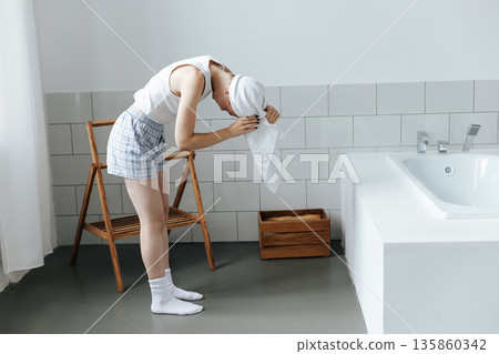 Young woman wrap white towel over head in bathroom Young woman wrap white towel over head in bathroom 135860342