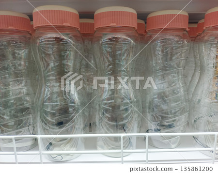 Clear Plastic Water Bottles with Pink Caps in a Row on Store Shelf for Daily Hydration Clear Plastic Water Bottles with Pink Caps in a Row on Store Shelf for Daily Hydration 135861200