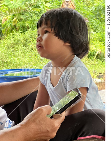 Portrait of a beautiful Asian little girl learning how to use a mobile phone. 135862160