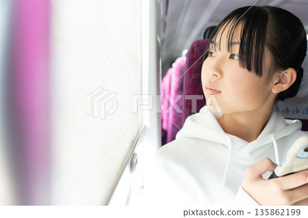 一個十幾歲的女人從火車窗外往外看 135862199