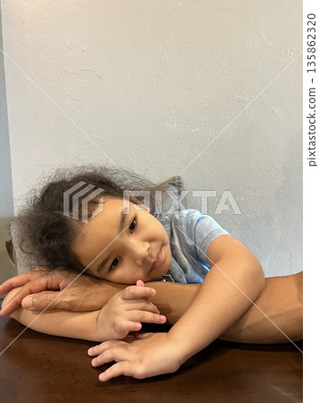 Portrait of a beautiful Asian little girl with curly hair in a blue shirt Portrait of a beautiful Asian little girl with curly hair in a blue shirt 135862320