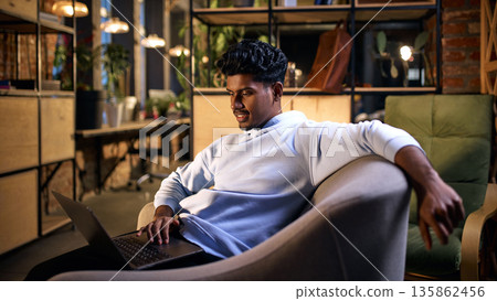 Young man working on laptop in modern coworking environment. 135862456