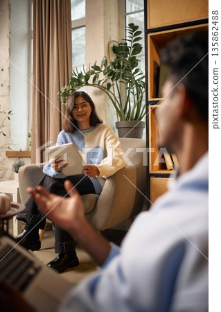 Woman holding tablet during informal meeting in modern office lounge. Woman holding tablet during informal meeting in modern office lounge. 135862488