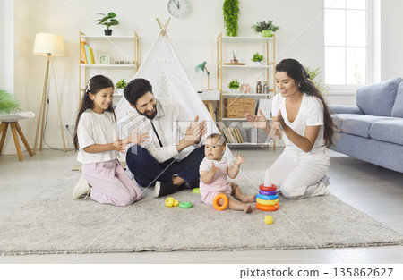 Happy parents and children playing with toys, clapping hands and having fun together 135862627