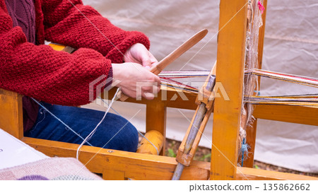 Artisan weaving traditional patterned belt on loom 135862662